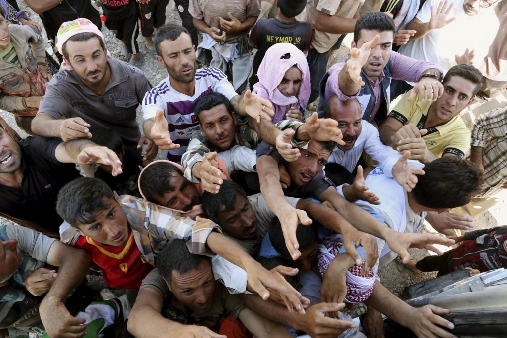 פליטים יזידים מעירק מתחננים לסיוע הומניטרי בגבול סוריה-עירק ב-10 לאוגוסט 2014 (AP Photo/ Khalid Mohammed)