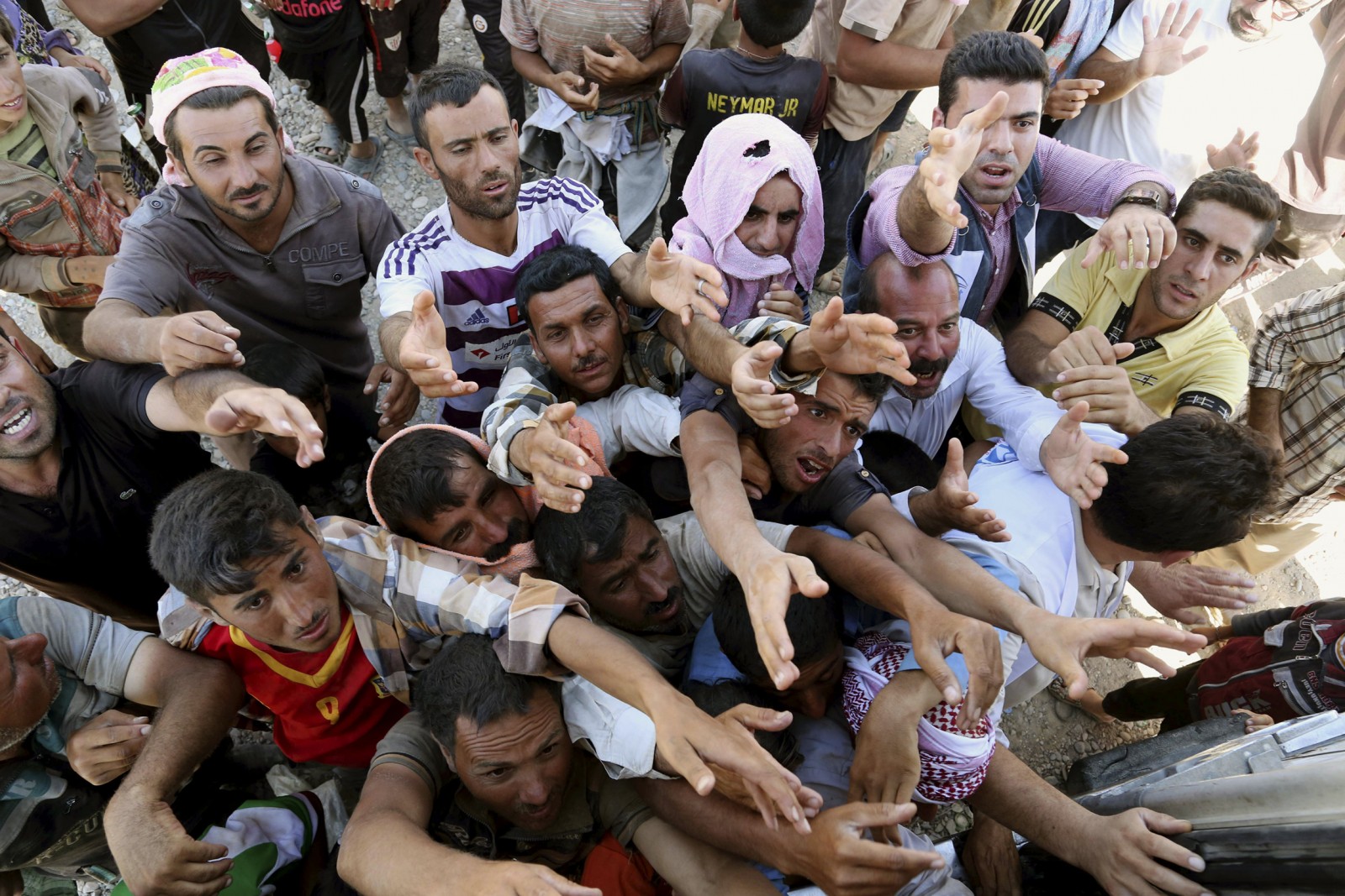 لاجئون ايزيديون من العراق يتوسلون للحصول على مساعدة إنسانية على حدود سوريا – العراق بتاريخ 10 آب 2014 (AP Photo/ Khalid Mohammed)