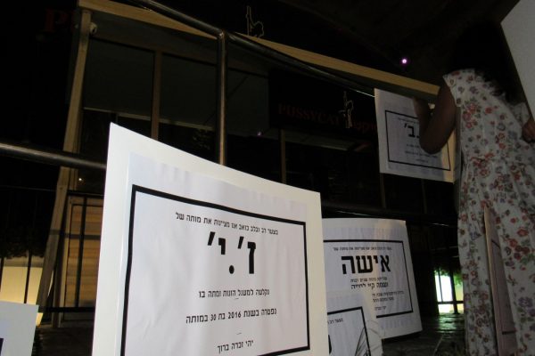 תולות שלטים על מועדון החשפנות "הפוסיקט", במחאה על סחר בגופן של נשים -זנות. (צילום: דבר ראשון).
