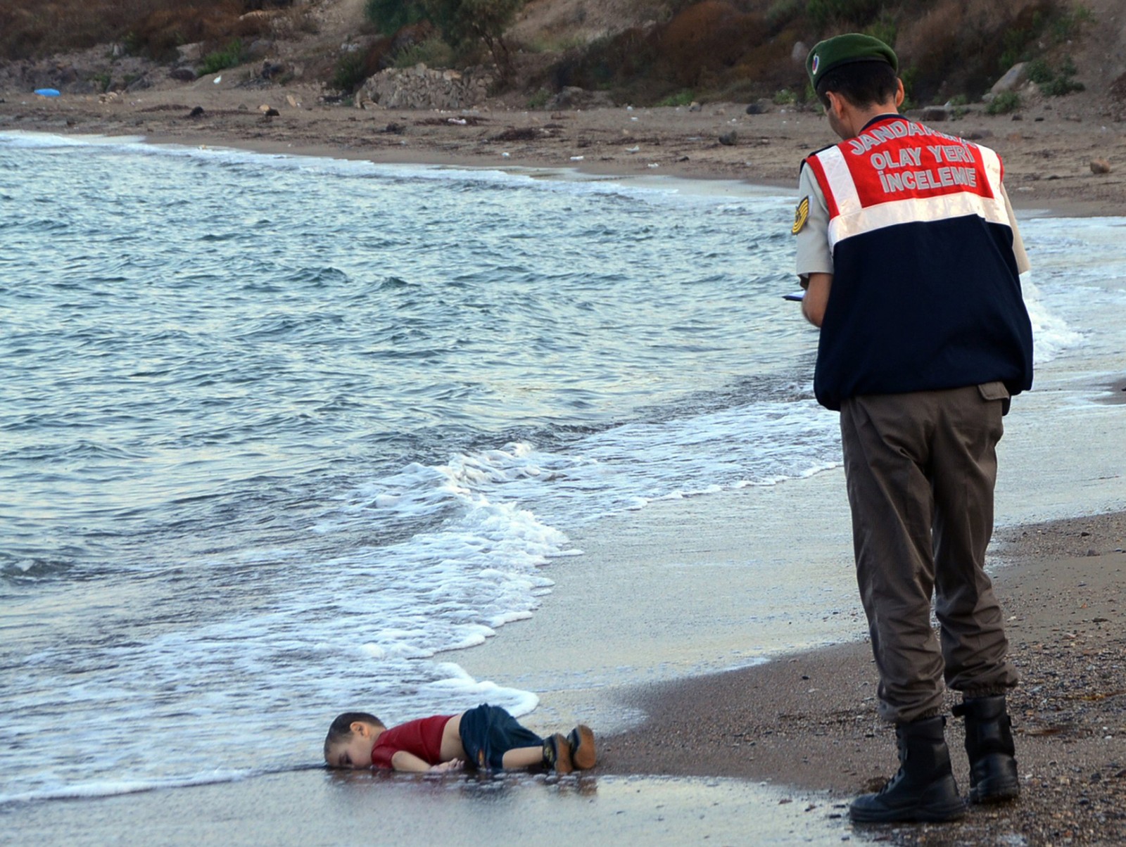 גופתו של איילן כורדי בן ה-3, שיחד עם משפחתו ברחו ממלחמת האזרחים בסוריה, על חוף הים בטורקיה, לאחר שטבע בעת ניסיון להגיע ליוון. ספטמבר 2015. (צילום: סוכנות AP).