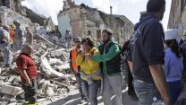אשה שביתה נהרס צועדת בין ההריסות בעיירה אמאטריס, שנפגעה הבוקר מרעידת אדמה (צילום: AP).