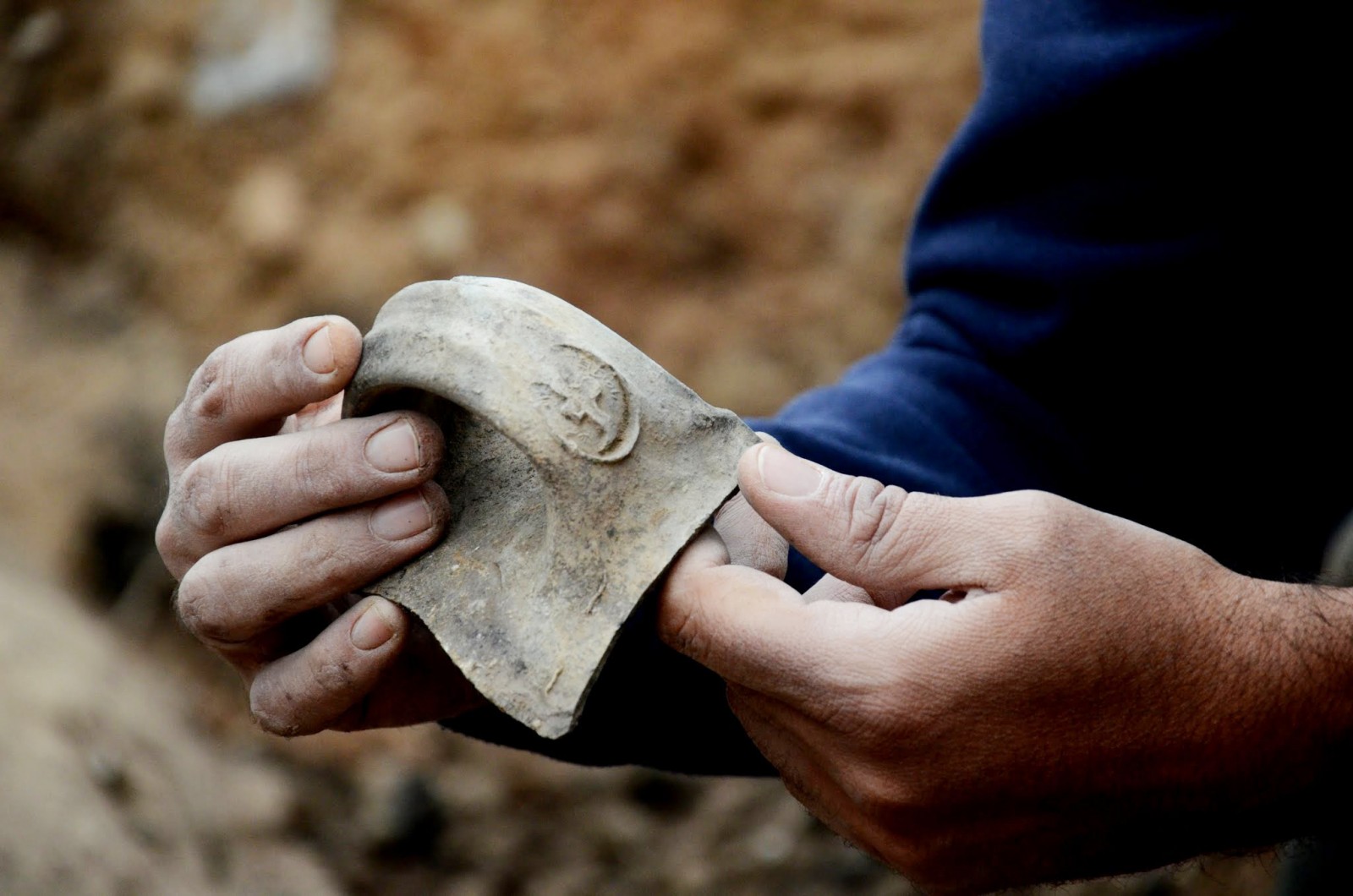 טביעת חותם על ידית קנקן "למלך חברן" בעת חשיפתה בשטח (צילום: יולי שוורץ / רשות העתיקות).