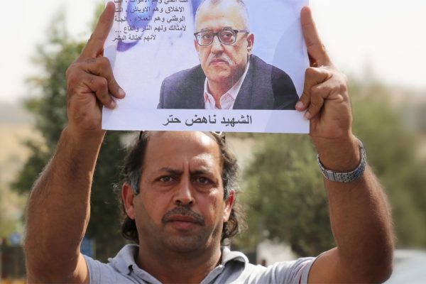 אזרח ירדני מחזיק בתמונה של נהאד חאתר אחר ההתנקשות בו (צילום: AP Photo/Raad Adayleh).