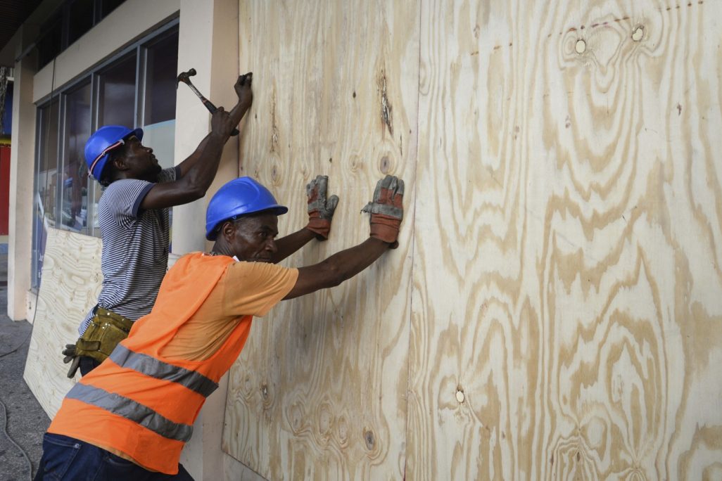 פועלים ממסמרים לוחות עץ על חלונות ראווה של חנויות לקראת פגיעתו של הוריקן מת'יו בקינגסטון, ג'מייקה (צילום: AP).