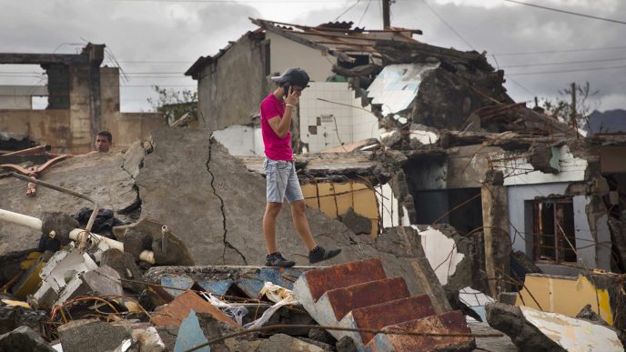 צעיר הולך בהריסות ביתו שהוחרב ע״י ההוריקן מת׳יו בקובה (צילום: סוכנות AP).