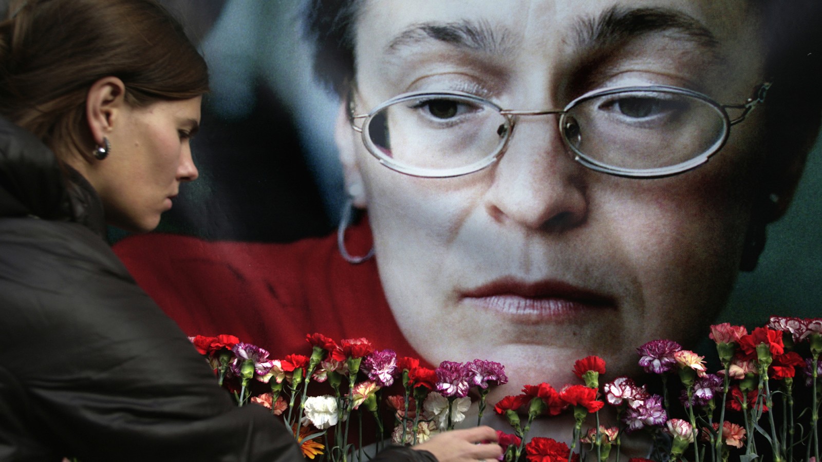 אישה מניחה פרחים למרגלות דיוקן של העיתונאית אנה פוליטקובסקיה שנרצחה ב2006 (צילום: סוכנות AP).