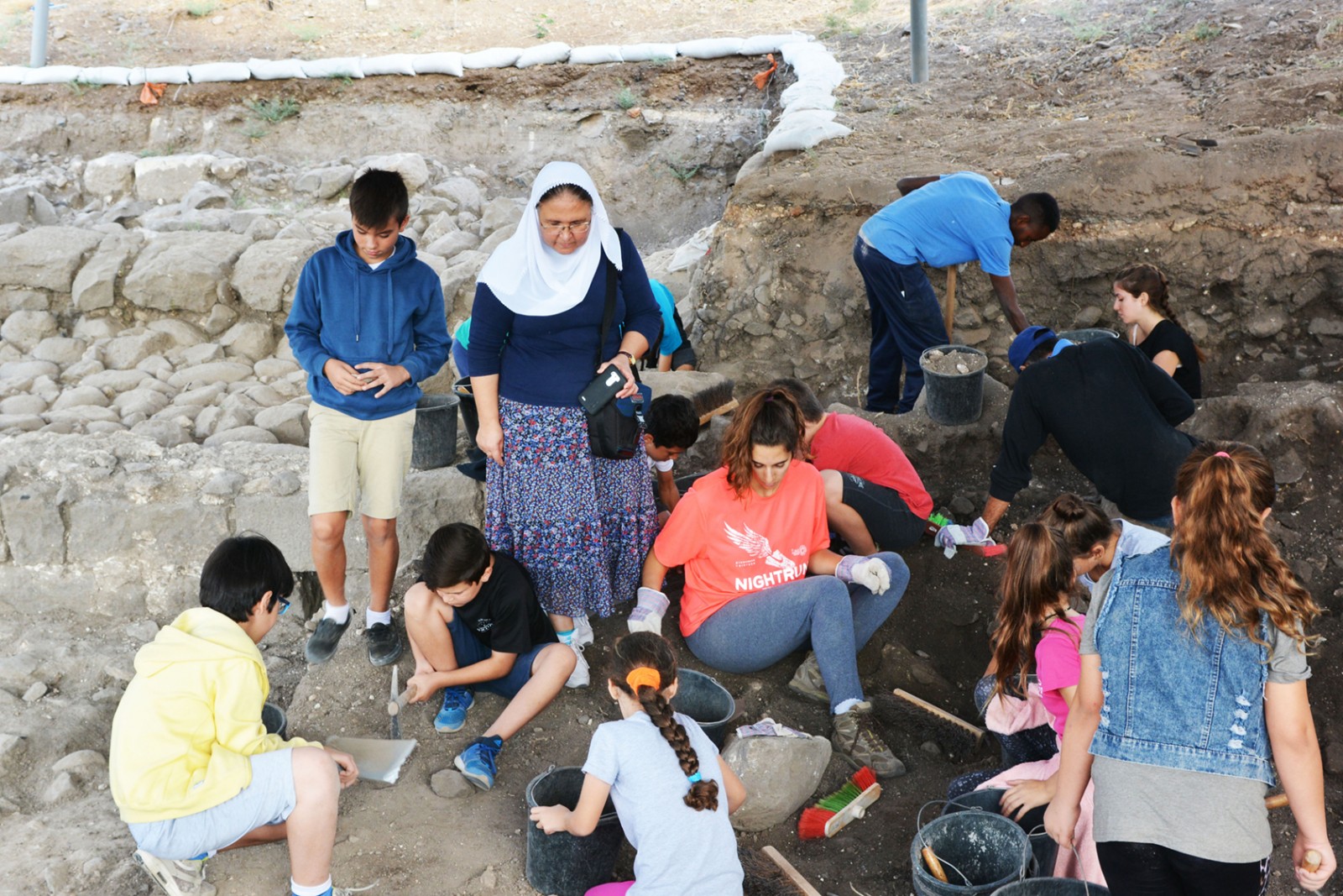 ילדי בית ספר "תינאל" בכפר כמא עם המורה סילביה אישליין, מתנסים בעבודת הארכיאולוגים. (צילום: גלעד צינמון, באדיבות רשות העתיקות)