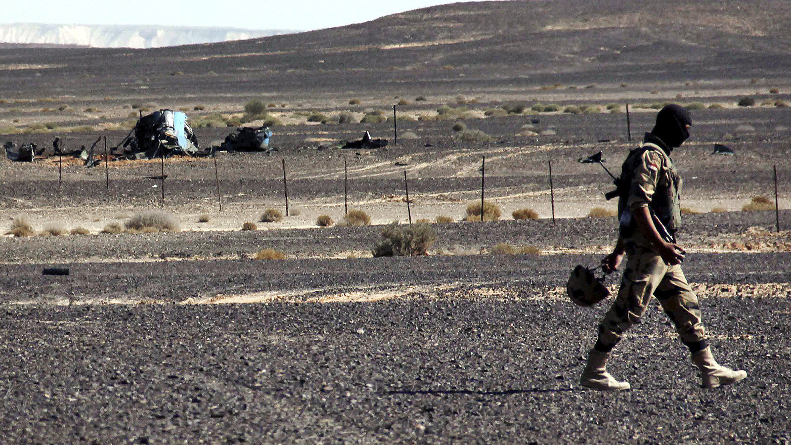 חייל מצרי עובר ליד הריסות המטוס הרוסי שהופל מעל סיני (צילום ארכיון: סוכנות AP).