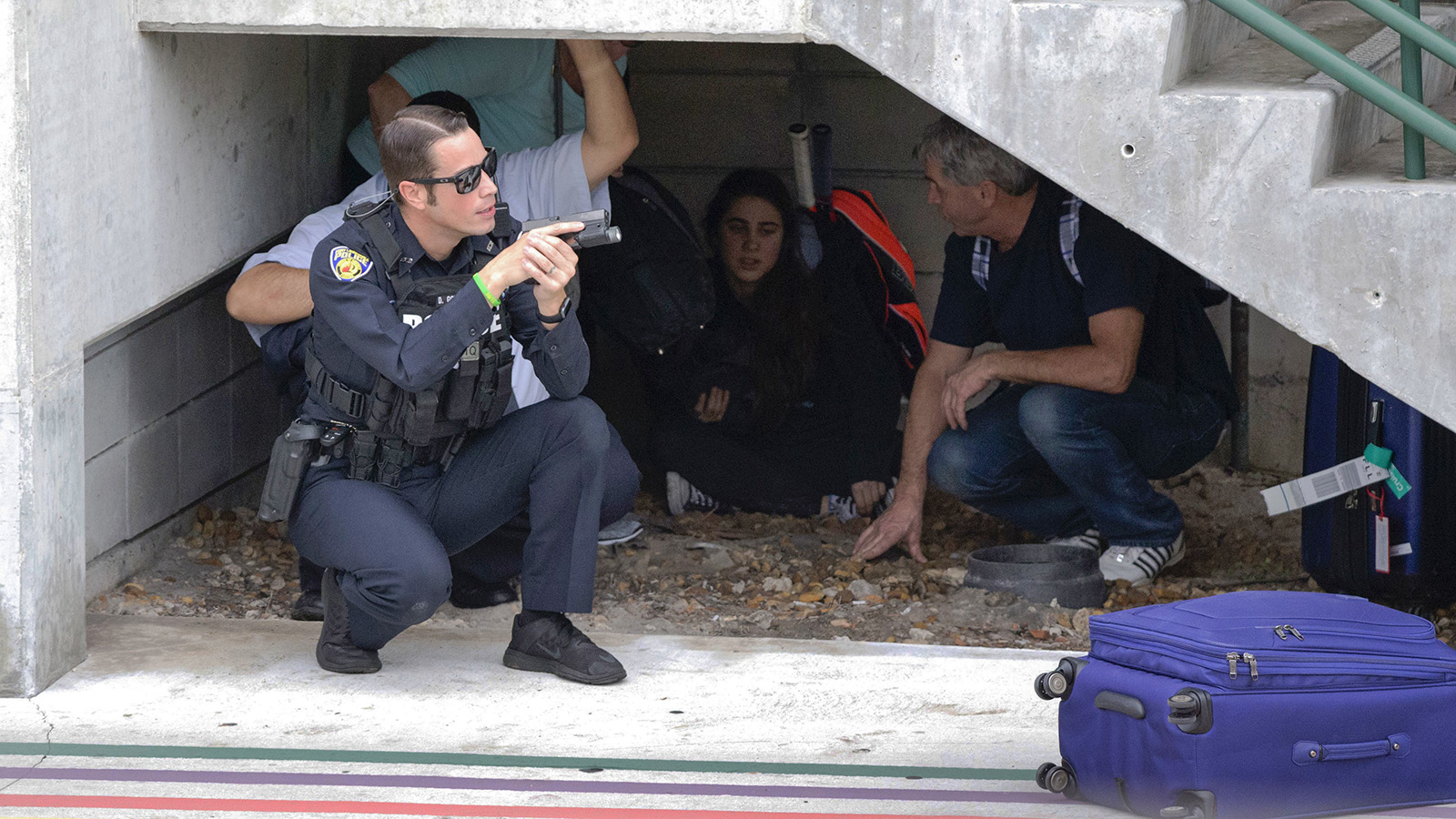 שוטר מגינים על אזרחים באיזור אחסון בשדה התעופה בפלורידה בעקבות הירי (צילום: סוכנות AP).