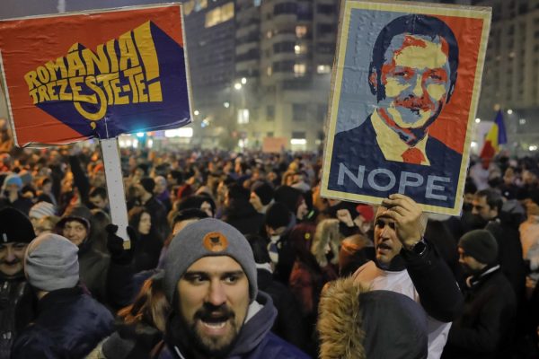 מפגינים נושאים שלטים עם הכיתוב "רומניה התעוררי!" ודיוקנו של ראש מפלגת השלטון הסוציאל דמוקרטית (צילום: סוכנות AP)