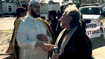 דר' רוברט לאוב, ועמיתו דר' שהיד חאסימי, מנהיגי הקהילות היהודית והמוסלמית בויקטוריה, על רקע המסגד השרוף (באדיבות אלה טרייסי אוליבר).