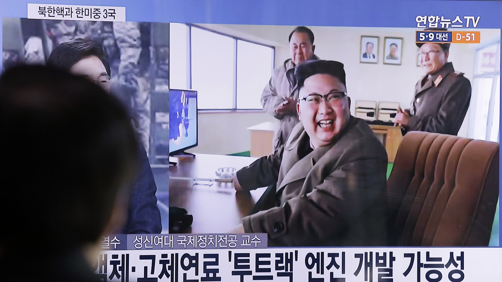 אדם צופה בתמונה של מנהיג קוריאה הצפונית, קים ג'ונג און, באתר ניסוי מנוע הטילים. ארכיון (צילום: AP Photo/Ahn Young-joon)