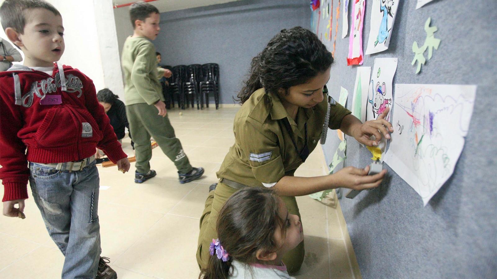 Soldier helps children pass the time in the safety of a bomb shelter in Ashkelon. Archive. March 21, 2017. (Flash90/Yossi Zamir)