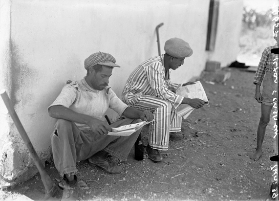 שעת מנוחה פועלים קוראים עיתון, כפר אלישיב, 1939. אוסף הצילומים הייחודי של זולטן קלוגר (אתר ארכיון המדינה).
