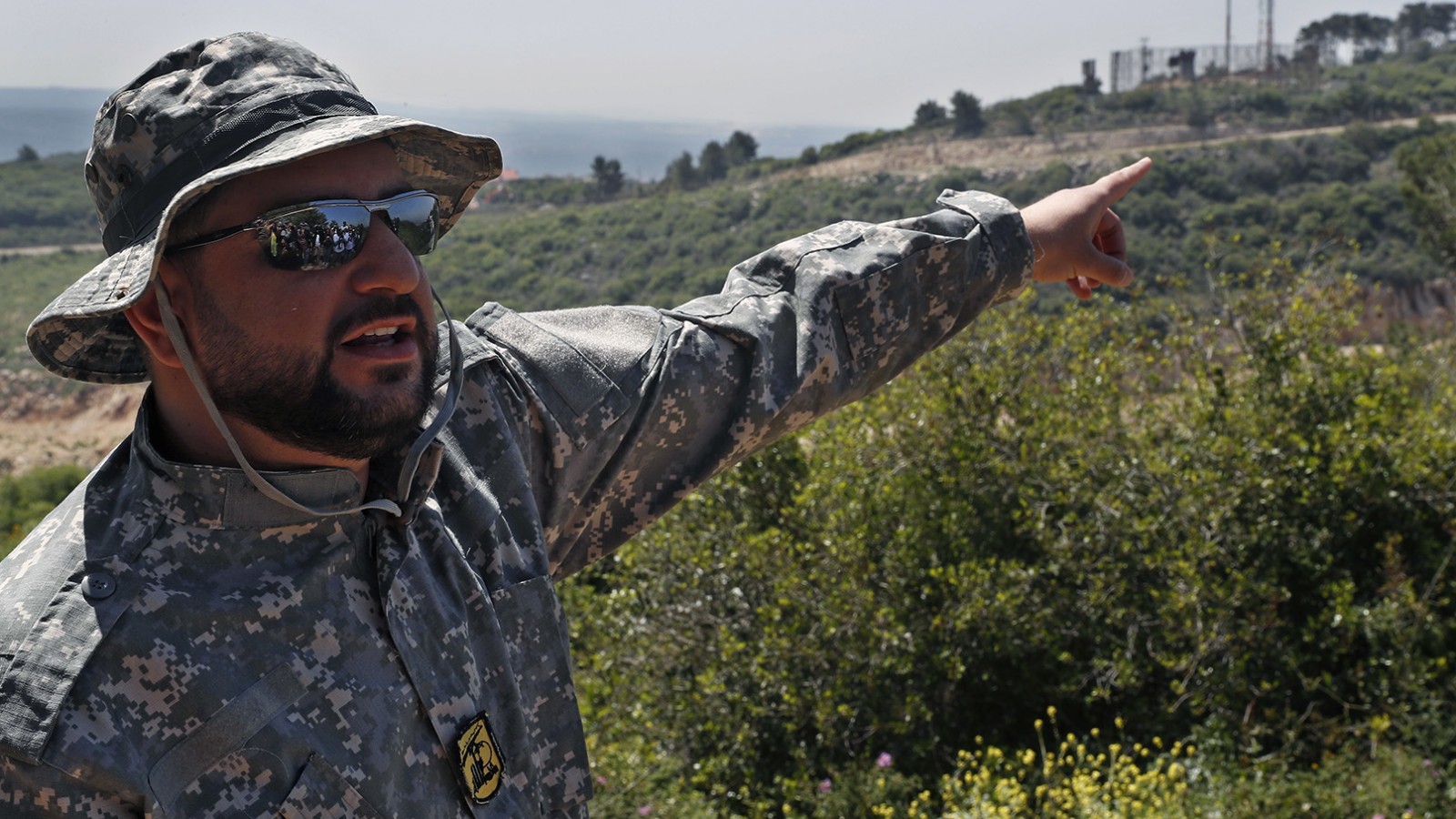 קצין חיזבאללה מצביעי על עמדת צה&quot;ל בגבול לבנון בסיור שערך ארגון חיזבאללה לתקשורת (צילום: AP Photo/Hussein Malla).