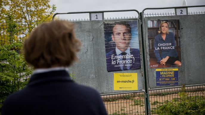 אישה מסתכלת על פוסטרים של עמנואל מקרון ומרין לה פה מחוץ לקלפי בצרפת לקראת הסיבוב השני בבחירות לנשיאות צרפת (צילום: יונתן זינדל/ פלאש 90).