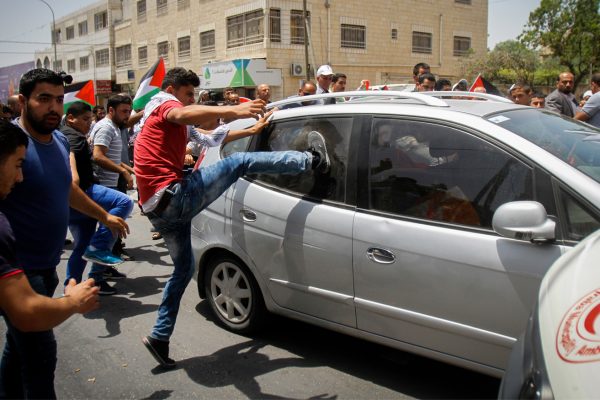 מפגינים פלסטינים מקיפים רכב של מתנחל שע"פ עדויות ירה במפגין ובעיתונאי (צילום: נאסר ישתעיא / פלאש 90).