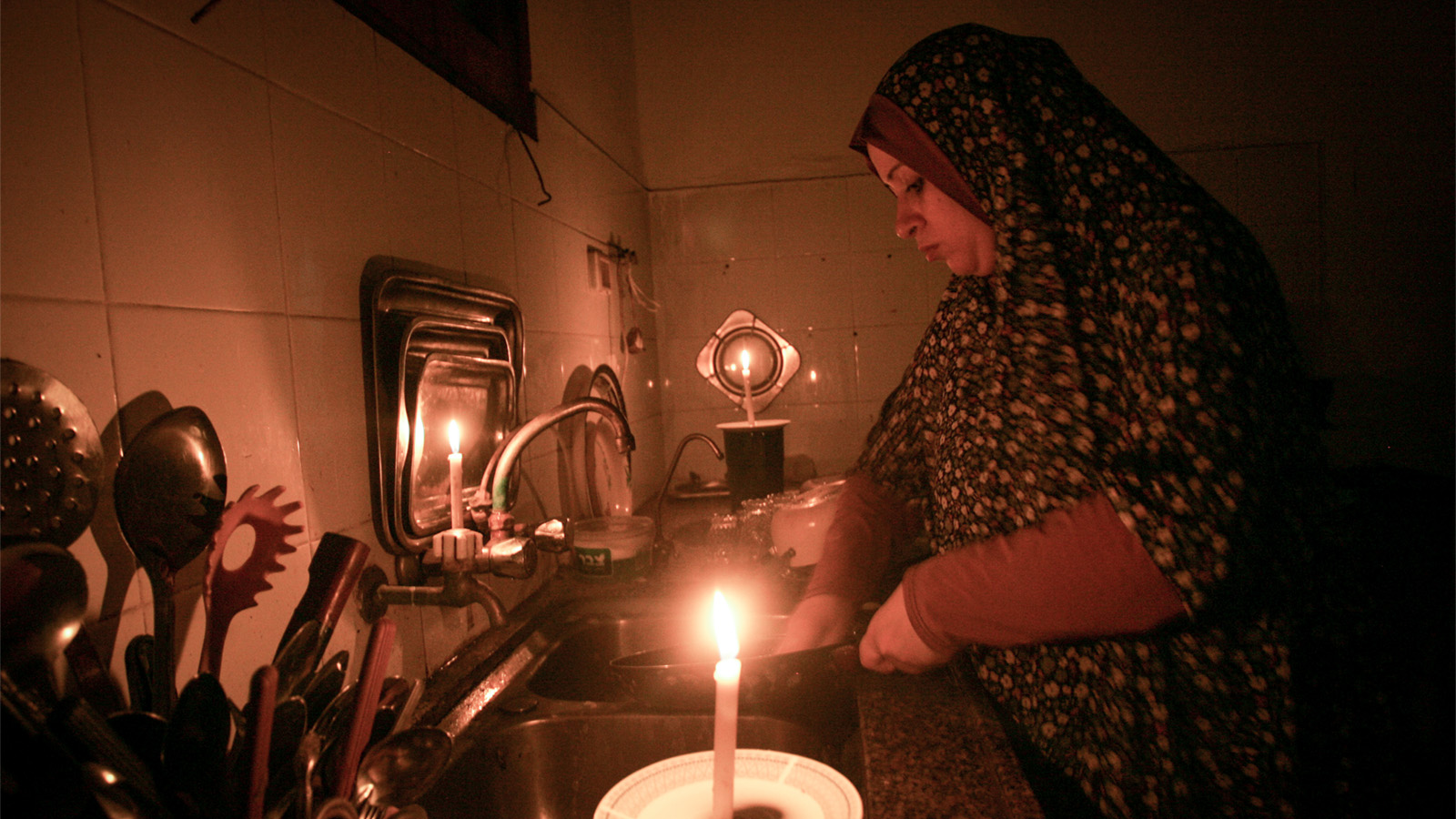אישה פלסטינאית בעזה שוטפת כלים לאור נרות עקב בעיות באספקת החשמל (צילום: עבד אל ראחים כ'תיב/ פלאש 90).
