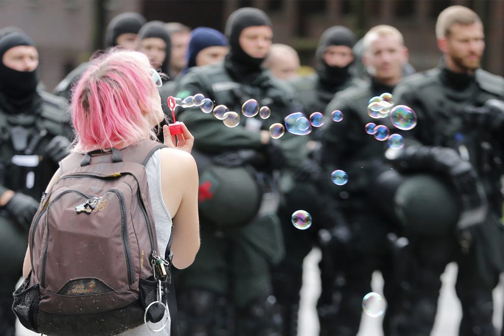 מפגינה נושפת בועות סבון מול שוטרים מהיחידה לפיזור הפגנות (צילום: AP Photo/Michael Probst).