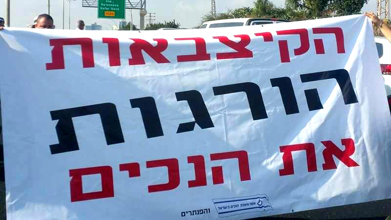 שלט בהפגנה (צילום: דף הפייסבוק 'מטה מאבק הנכים').