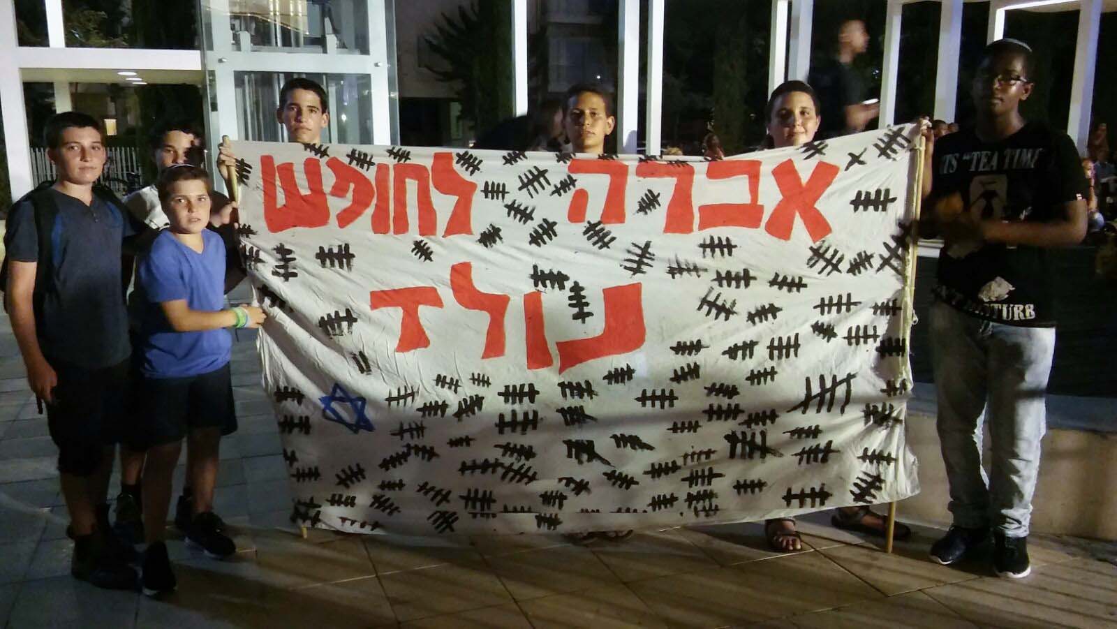 עומר וחבריו מלוד, עם שלט שהכינו בעצרת לציון 3 שנים בשבי של אברה מנגיסטו (צילום: יהל פרג')