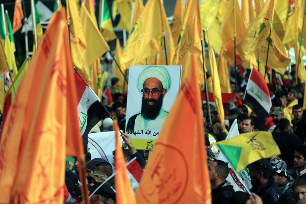 מיליציות שיעיות צועדות בבגדד עם דגלי שיעים ותמונות של השיח נימר אל נימר  במחאה על הוצאתו להורג בערב הסעודית. 6 בינואר 2016 (צילום: AP Photo/Khalid Mohammed)
