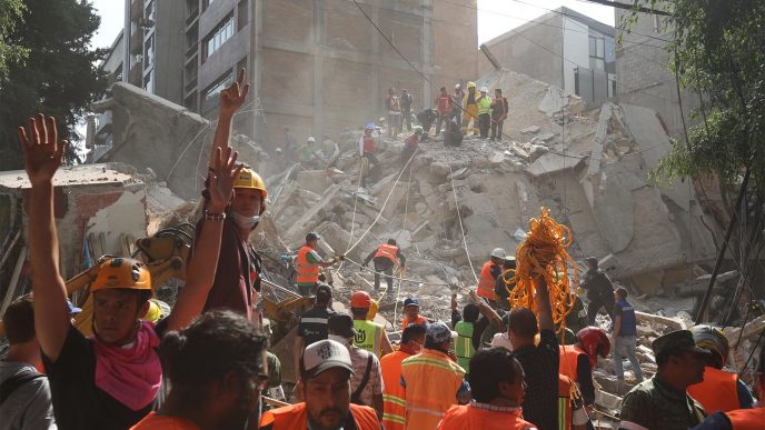 מחלצים מבקשים שקט מקהל צופים בעודם מחפשים ניצולים בין הריסות בניין מגורים במקסיקו סיטי לאחר רעידת אדמה בעוצמת 7.1 בסולם ריכטר (AP Photo/Gustavo Martinez Contreras)