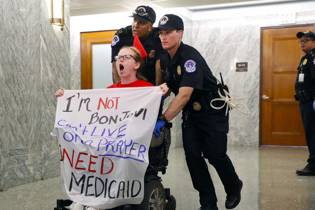 שוטרים בארה"ב דחופים גברת על כיסא גלגלים מחוץ לאולם של וועדת הכספים של הסנאט האמריקאי (צילום: AP Photo/Pablo Martinez Monsivais).