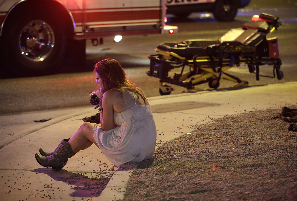 אישה יושבת על המדרכה מחוץ לזירת הירי בפסטיבל זמר הקאנטרי בלאס וגאס (צילום: AP Photo/John Locher).