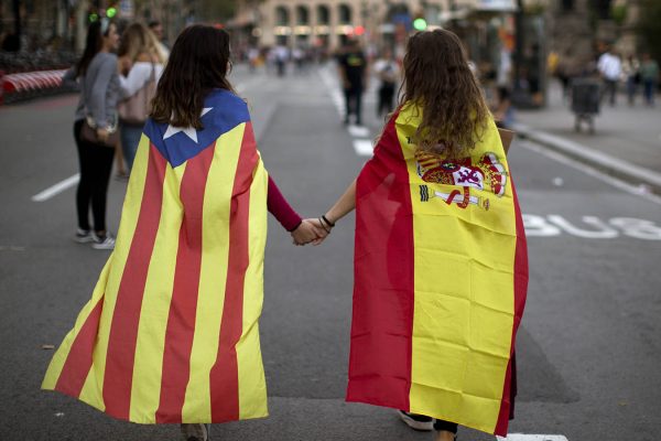 בנות נוער עם דגלי ספרד וקטלוניה אוחזות ידיים בהפגנה נגד האלימות המשטרתית  במשאל העם. (צילום: AP Photo/Emilio Morenatti)