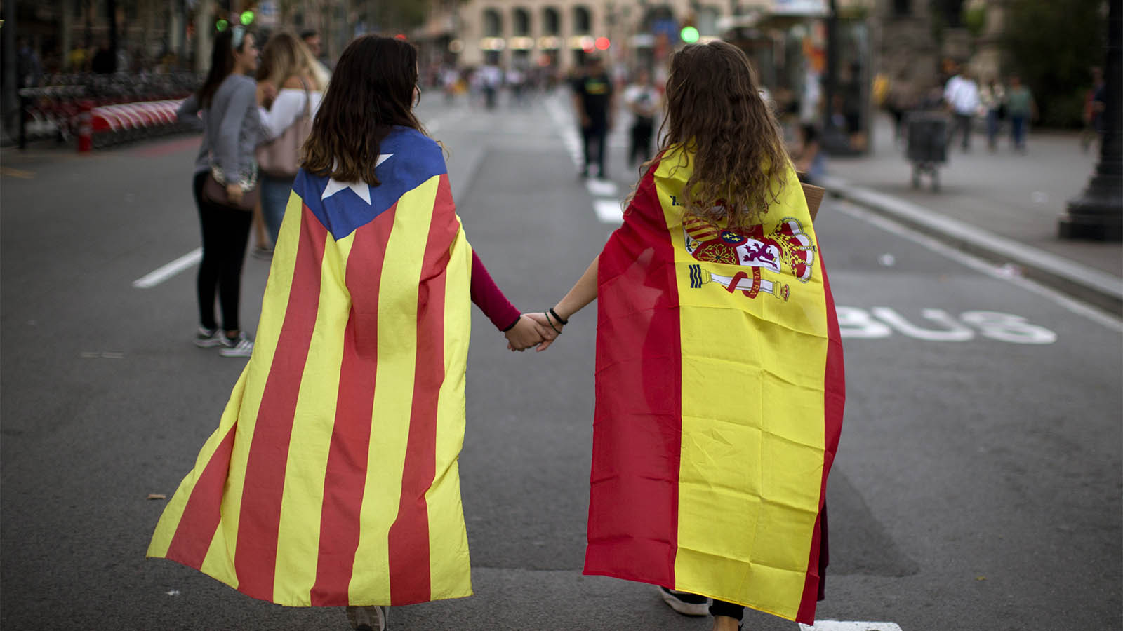 בנות נוער עם דגלי ספרד וקטלוניה אוחזות ידיים בהפגנה נגד האלימות המשטרתית במשאל העם. (צילום: AP Photo/Emilio Morenatti)