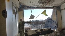 חייל מכוחות מ-SDF מנופף בדגל כורדי בבניין בעיר א-רקה לאחר קרב עם כוחות דאע"ש (צילום: Syrian Democratic Forces via AP)
