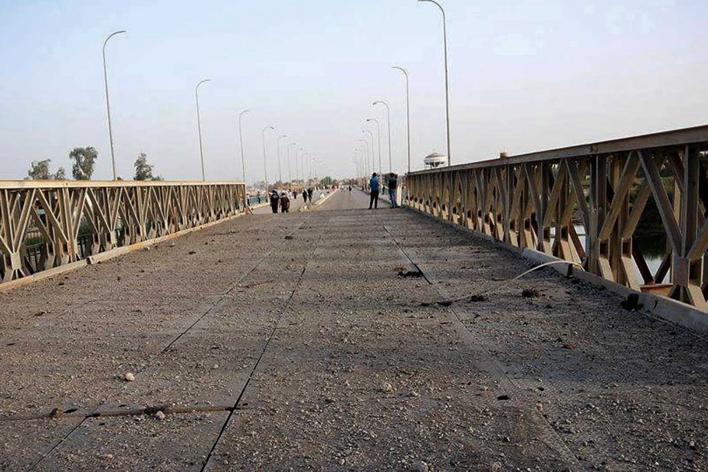 אנשים מבקרים גשר על נהר הפרת שהופצץ על ידי דאע"ש, יוני 2015. (צילום: AP Photo)