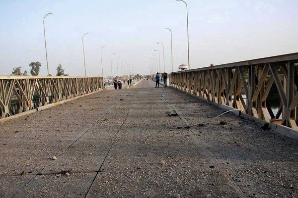 אנשים מבקרים גשר על נהר הפרת שהופצץ על ידי דאע"ש, יוני 2015. (צילום: AP Photo)