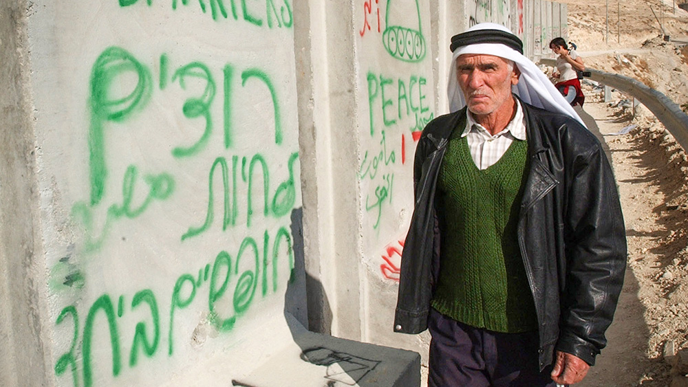 פלסטיני בסמוך לגרפיטי על גדר ההפרדה (צילום: שרון פרי / פלאש 90).