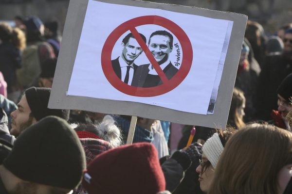 Protestors hold a poster with new Chancellor Sebastian Kern and new Vice Chancellor Heinz-Christian Strache at a demonstration during the swearing-in ceremony of the new Austrian government led by a conservative and a nationalist party in Vienna, Austria, Monday, Dec. 18, 2017. (AP Photo/Ronald Zak)