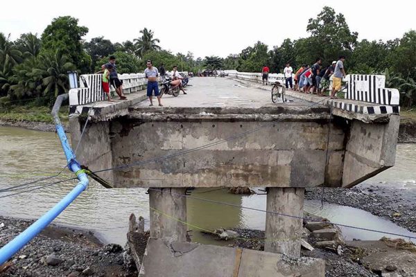 אנשים מתאספים ליד גשר שנהרס בעקבות סופת הטייפון בפיליפינים 24 בדצמבר (צילום: AP Photo/Daisy Barimbao)