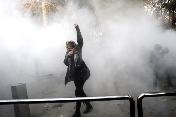 סטודנטית אירנית מפגינה בחצר האוניברסיטה בטהרן אל מול כוחות משטרה אירנים לפיזור הפגנות (צילום: AP Photo)