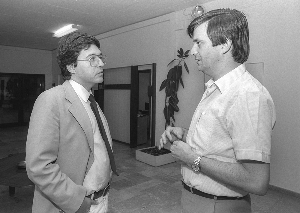 מזכיר הממשלה היוצא דן מרידור משוחח עם המזכיר הנכנס יוסי ביילין במסדרון משרד רה&quot;מ בירושלים בשנת 1985 (צילום: לע״מ).