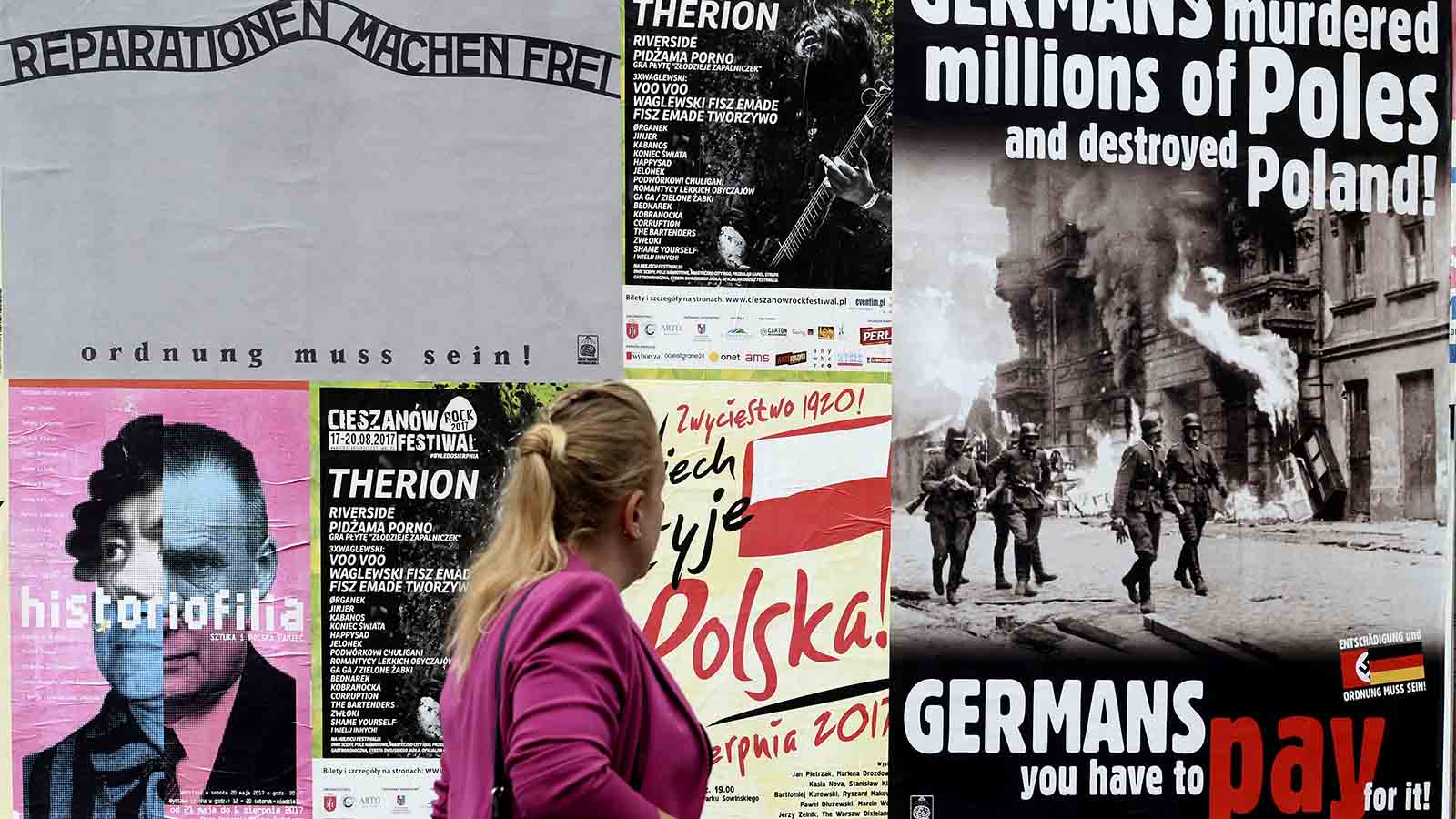 &quot;גרמנים רצחו מיליוני פולנים והשמידה את פולין – גרמנים אתם צריכים לשלם על זה!&quot; אישה פולניה חולפת על פני שלט חוצות בוורשה, פולין. אוגוסט 2017. (AP Photo/Alik Keplicz)