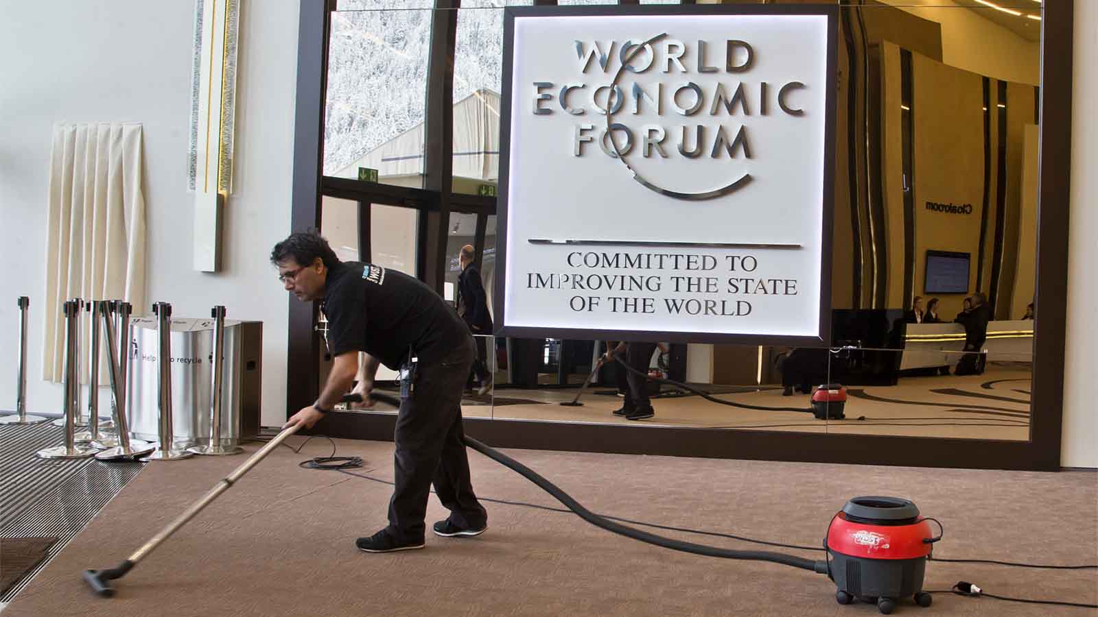 &quot;מחוייבים לשיפור מצב העולם&quot; עובד ניקיון מנקה את אולם הכנסים בדאבוס לקראת כנס הכלכלה העולמי , ינואר 2018(AP Photo/Michel Euler)