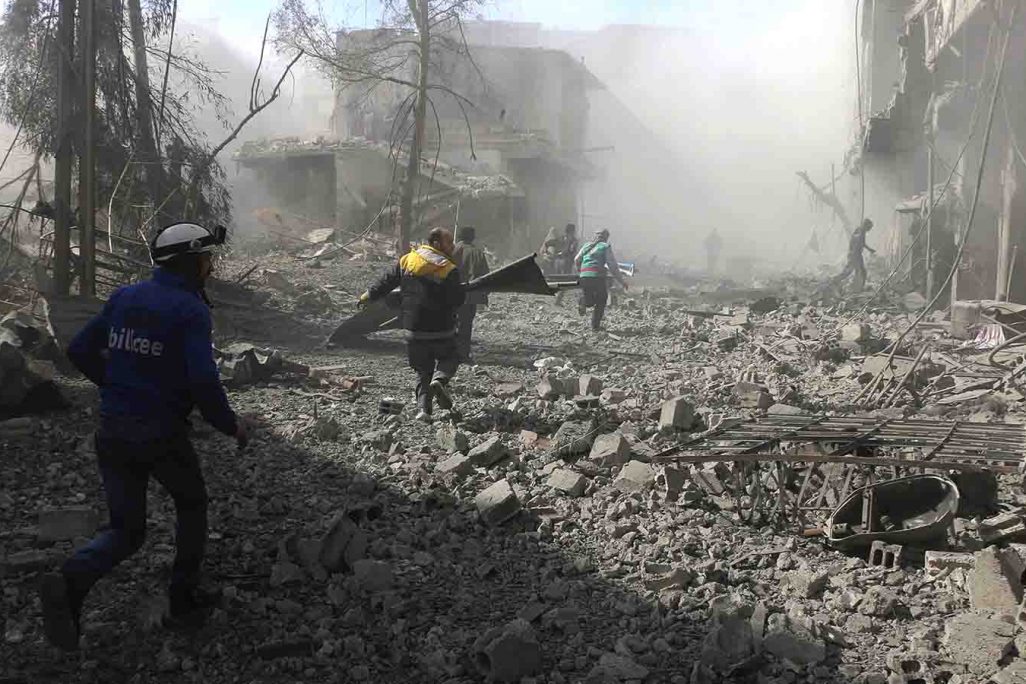 אנשי ארגון 'הקסדות הלבנות' רצים לחלץ נפגעים מבניין שהתמוטט בעוטא בפרברי דמשק, לאחר בהפצצות אויריות של צבא סוריה. 20 בפברואר (צילום: Syrian Civil Defense White Helmets via AP)