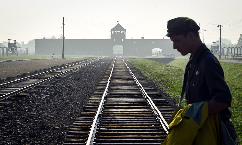 חייל פולני חוצה את המסילה העוברת בשטחי מחנה אושוויץ (צילום: AP Photo/Alik Keplicz, FILE).