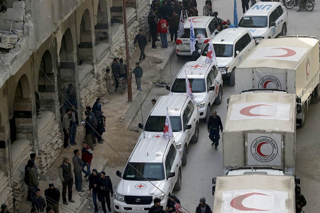 אזרחים ליד שיירת רכבים של הסהר האדום בסוריה, 5 במרץ 2018 (Syrian Red Crescent via AP)