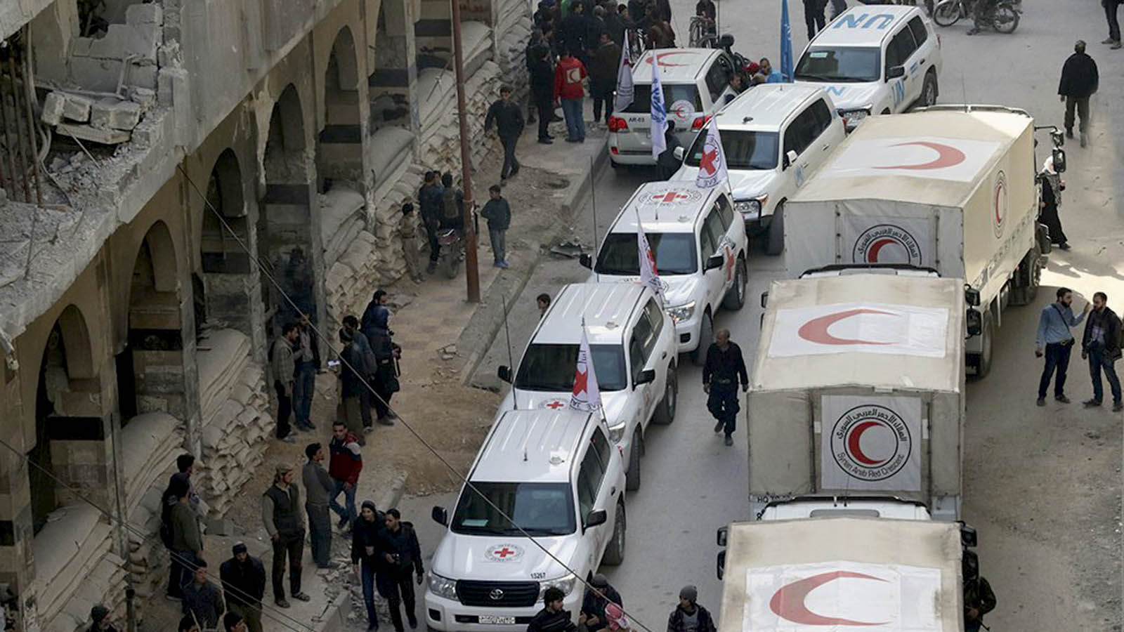 אזרחים ליד שיירת רכבים של הסהר האדום בסוריה, 5 במרץ 2018 (Syrian Red Crescent via AP)