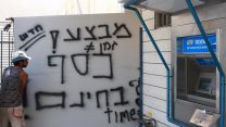 צעיר מחזיק שלט ליד כספומט בתל אביב, יולי 2011 (רוני שוצר /  פלאש90)