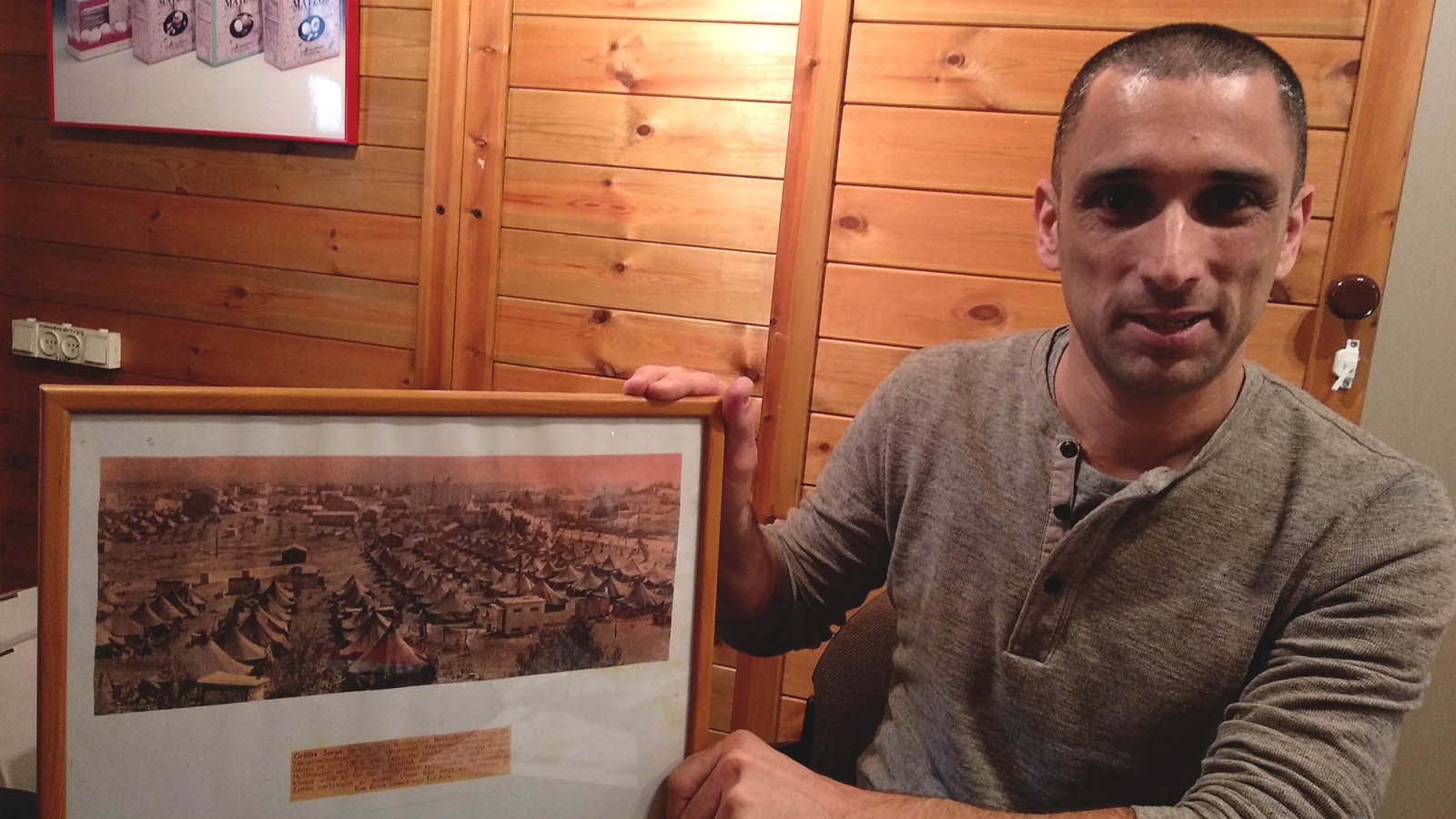 רועי וולף, סמנכ"ל מצות אביב, עם תמונת המפעל ליד אוהלי המעברה, באזור שלימים נהיה רח' זבוטינסקי (יעל אלנתן)