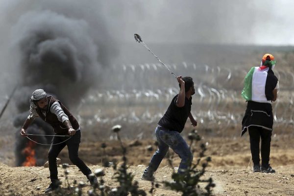 עזתים מיידים אבנים בהפגנות מול גדר הגבול בעזה 13 באפריל (AP Photo/ Khalil Hamra)