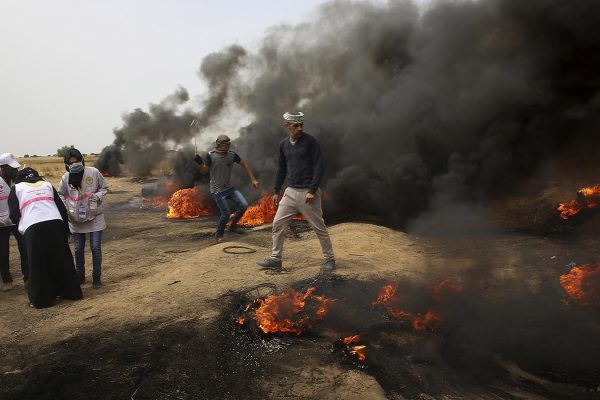 עזתים מיידים אבנים ושורפים צמיגים בהפגנות מול גדר הגבול. 20 באפריל (AP Photo/ Adel Hana)