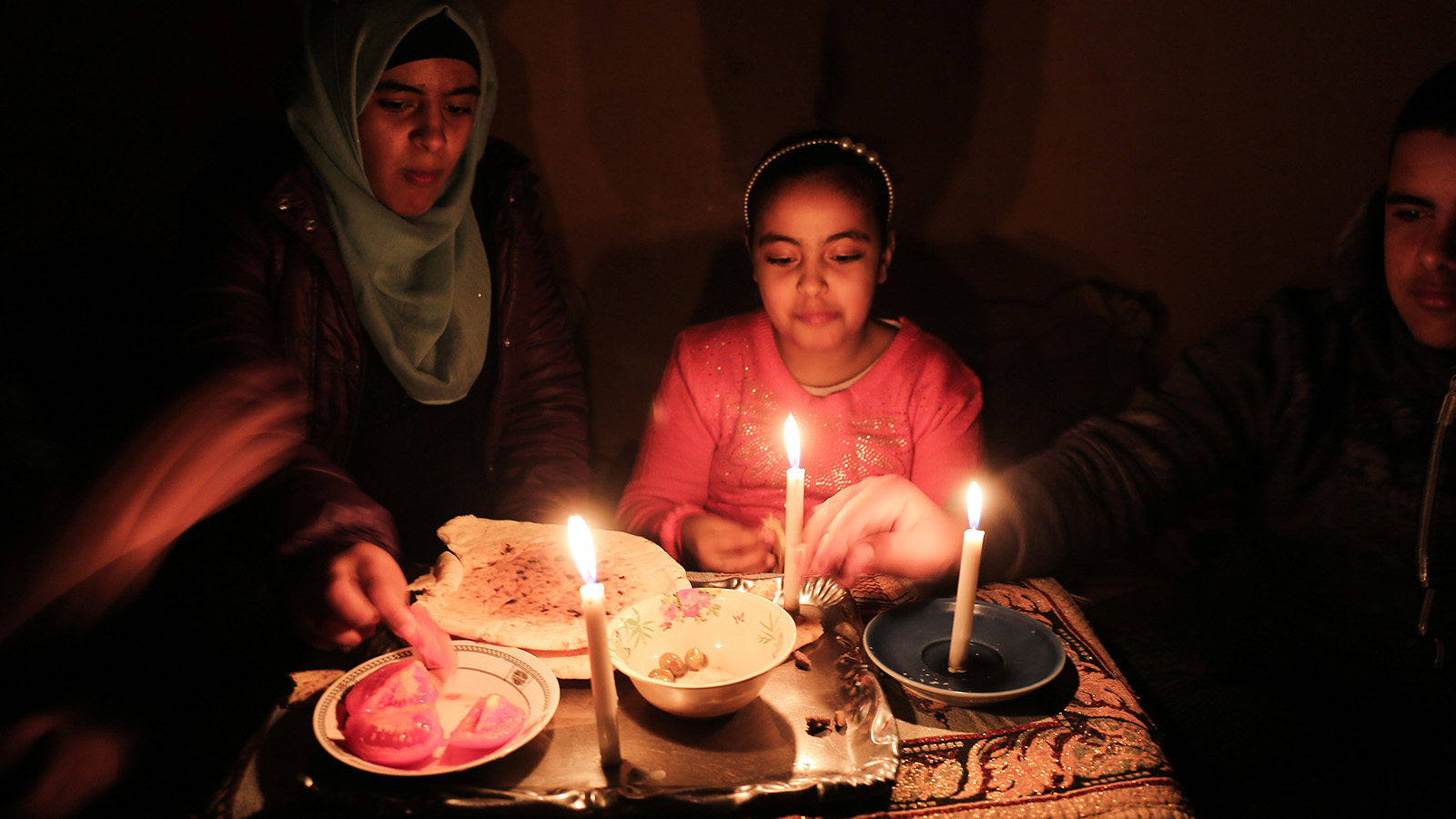 משפחה פלסטינית בארחות ערב לאור נרות בביתם במחנה הפליטים ברפיח, עקב מחסור בחשמל, 15 בפברואר 2018 ( Abed Rahim Khatib/ Flash90)